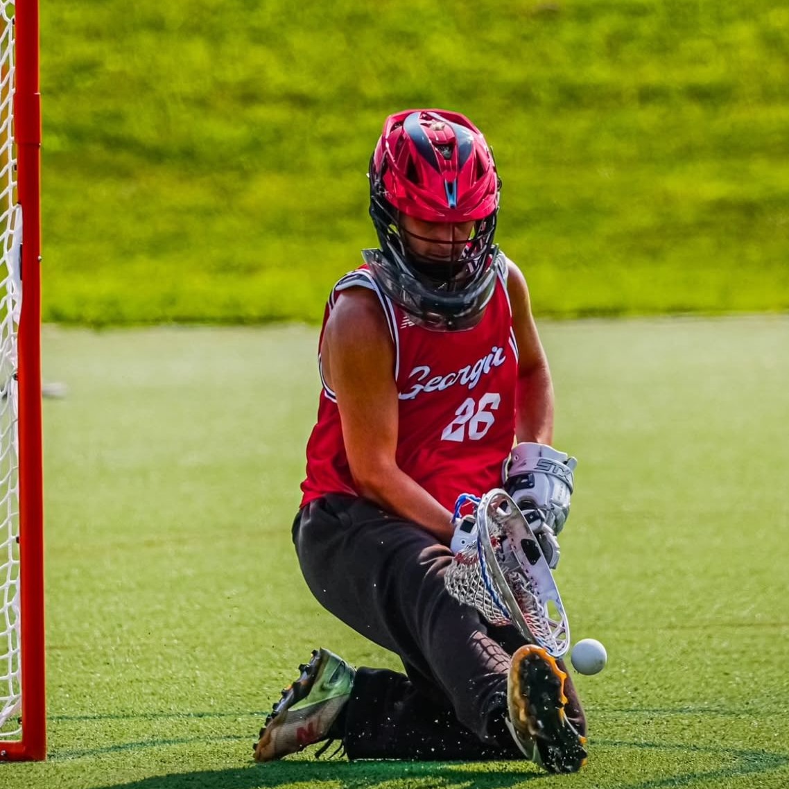 Youth lacrosse goalie blocking shot