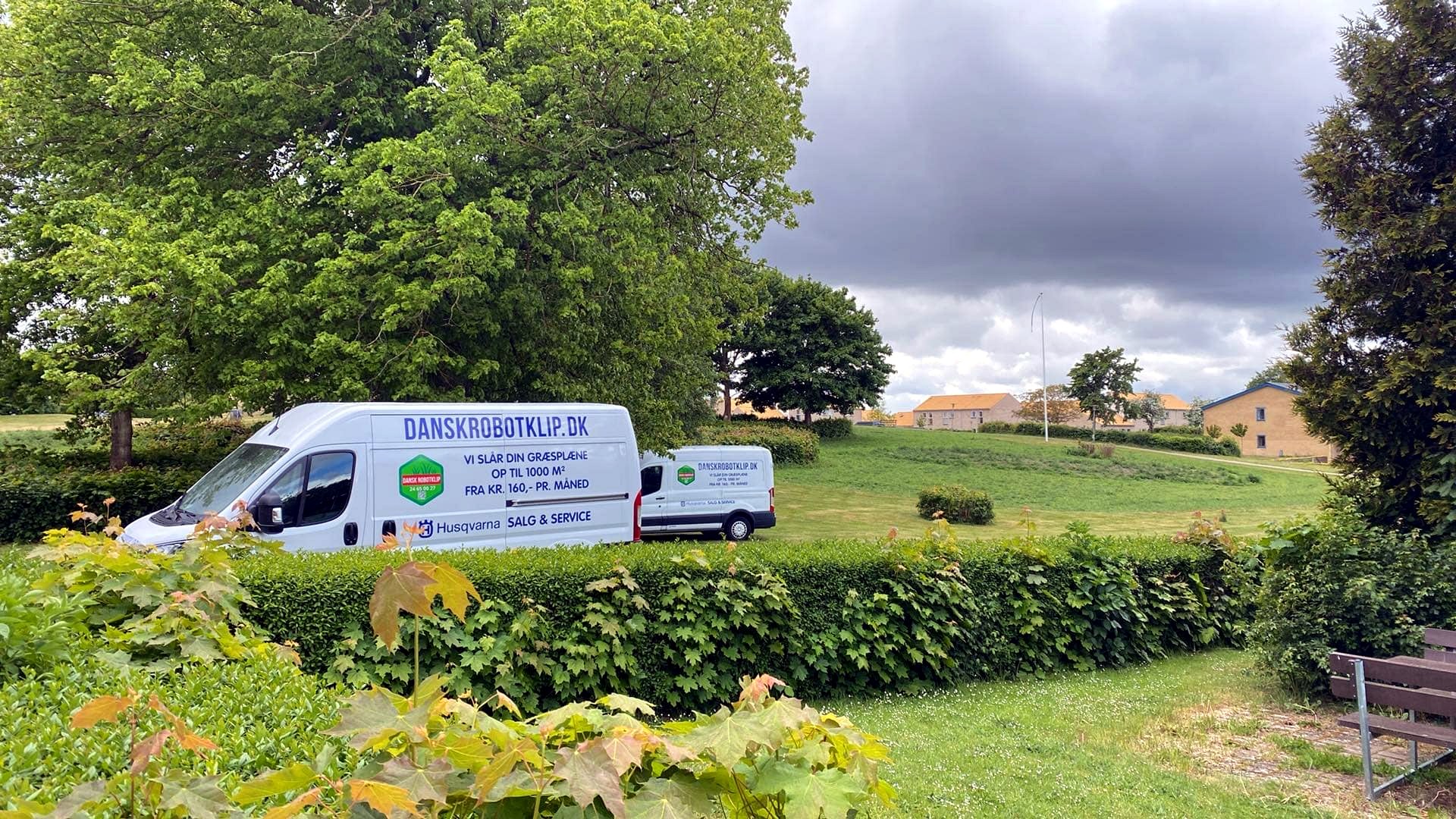 Dansk Robotklip servicevogne parkeret ved grønt område med tydelig branding for salg og service.