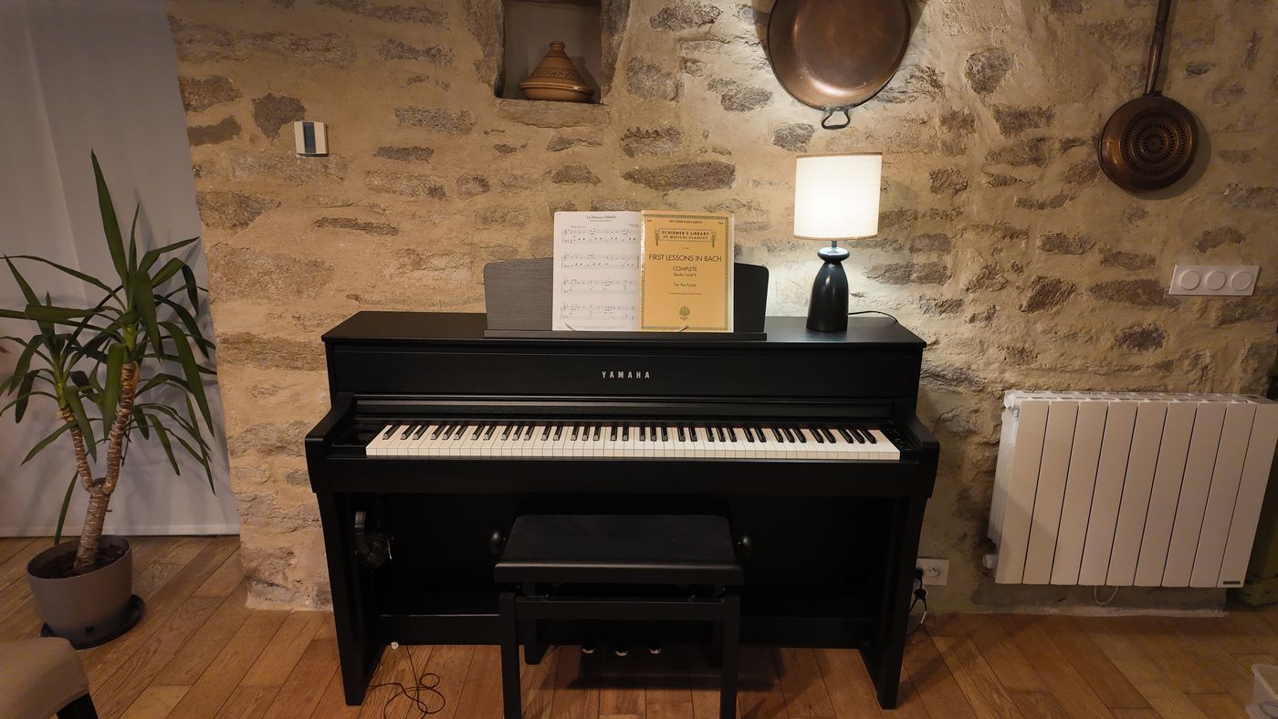 Un piano droit Yamaha contre le mur de pierre, éclairé par une lampe