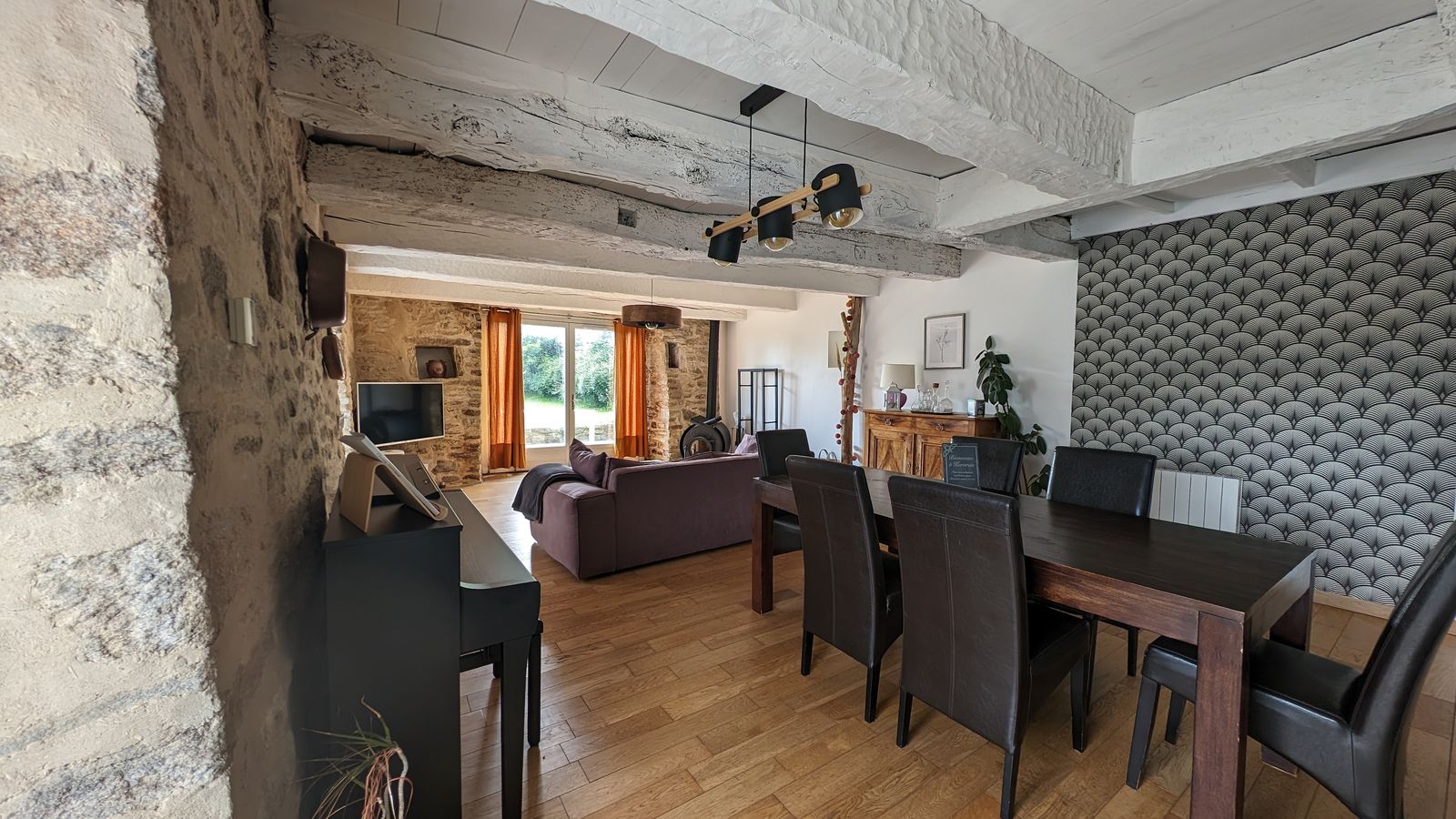 La salle à manger de Kervran, grande table en bois sous une suspension noire