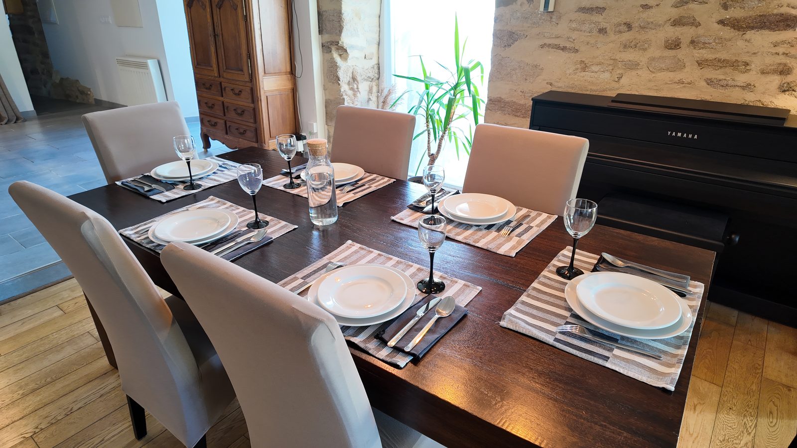 La table dressée pour six, le piano droit au fond de la pièce