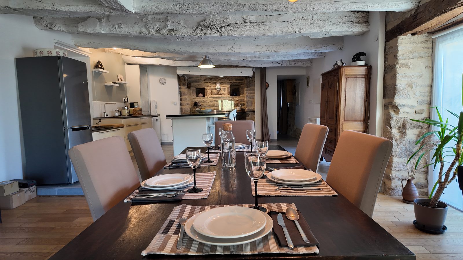 La grande table dressée pour six, la cuisine en enfilade derrière