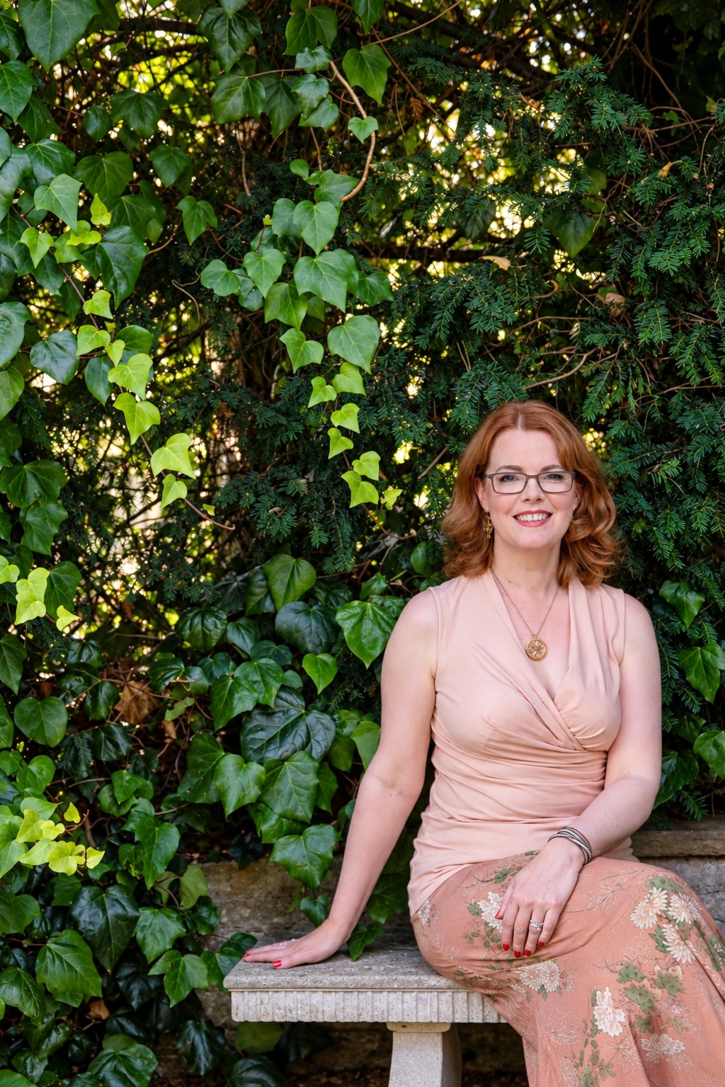 Dr Anne Whitehouse in a green dress beside a stone wall in the botanical gardens