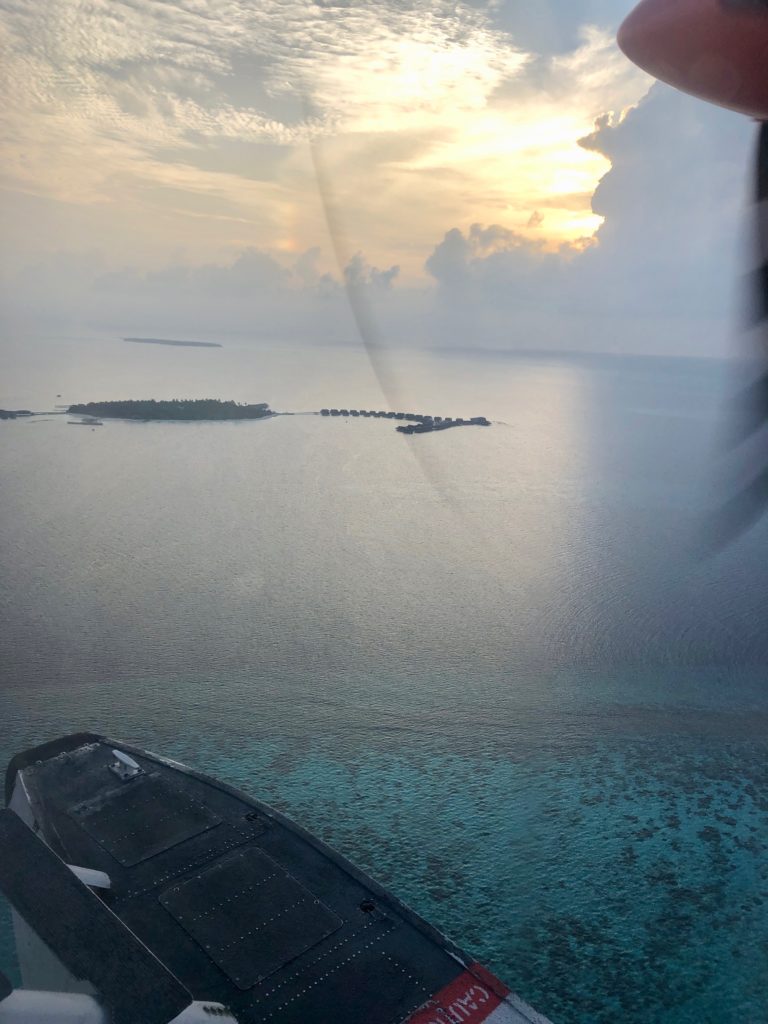 View of St. Regis Maldives resort from sea plane with sun setting
