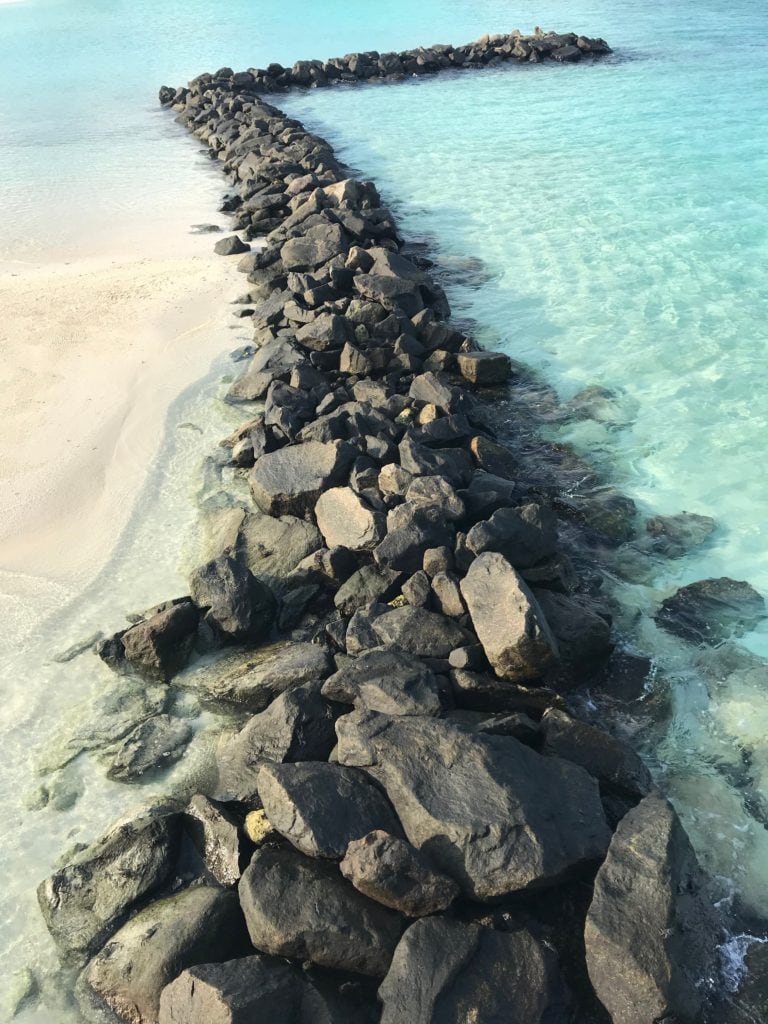 white sand and blue water with rocks at St. Regis Maldives 