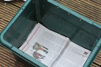 A layer of newspaper over the holes will prevent the worms falling out when you first put them in. You can put a drainage layer under this if you like - using eg stones or twigs - but this is not necessary. It can improve aeration, but it also has to be seperated from the worm compost when you harvest it which can be a bit of a hassle.